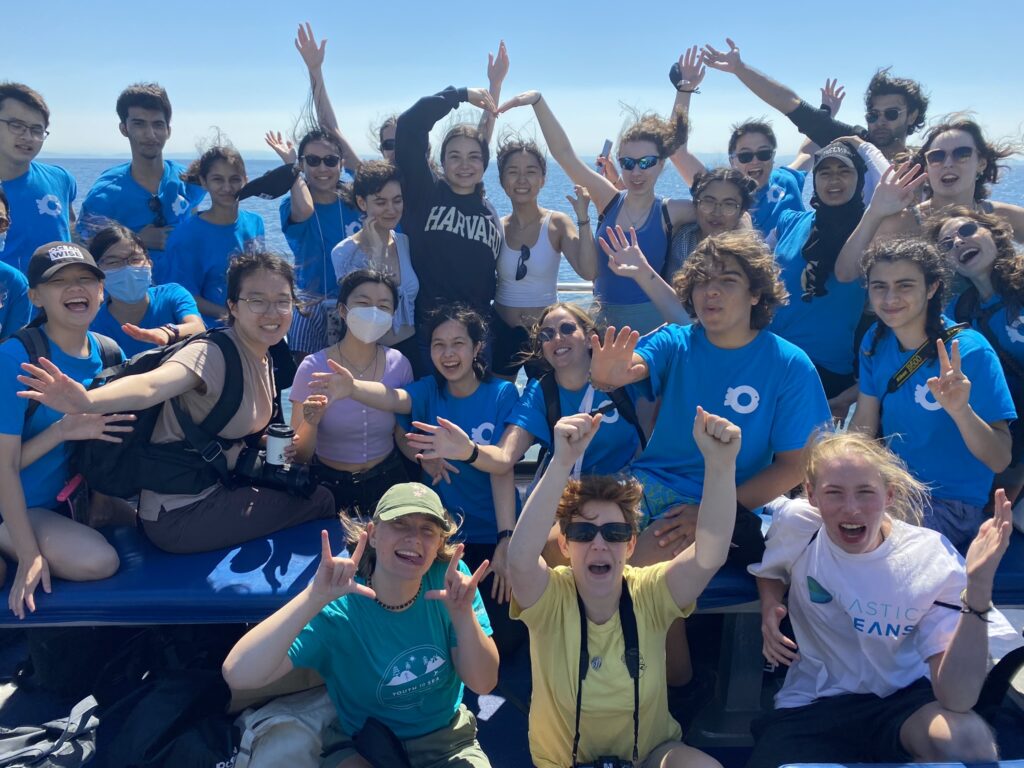 A group of participants smile and cheer on a whale watching boat